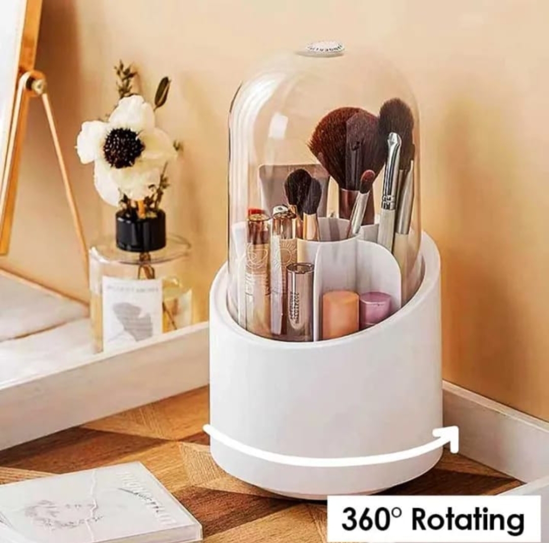 A hand lifting a clear dustproof lid off a white 360-degree rotating makeup brush organizer filled with various cosmetic brushes and lipsticks.