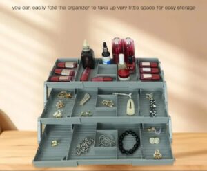 A 3-tier grey foldable organizer tray filled with cosmetics, lipsticks, and jewelry on a wooden desk.