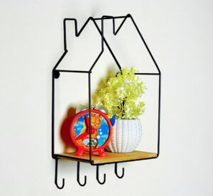 Black house-shaped metal wire wall shelf with wooden base and four hooks on a white wall